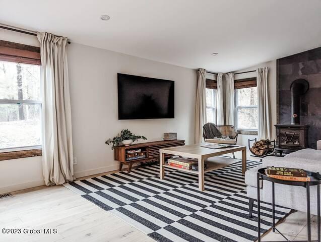 living room with a wood stove and light hardwood / wood-style flooring