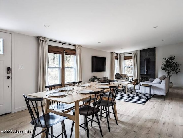 dining space with a wood stove, plenty of natural light, and light wood-type flooring