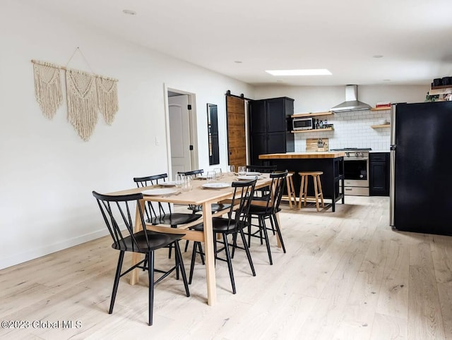 dining area featuring a barn door and light hardwood / wood-style flooring