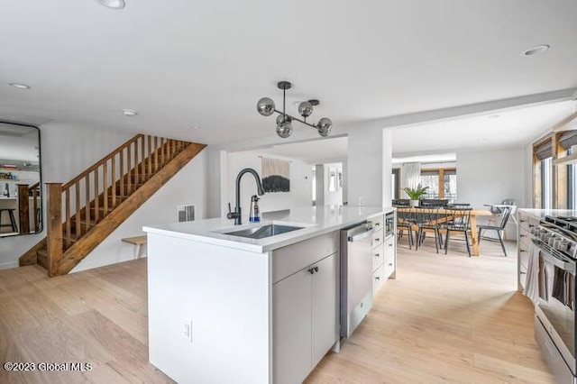 kitchen with white cabinetry, sink, a center island with sink, appliances with stainless steel finishes, and light wood-type flooring