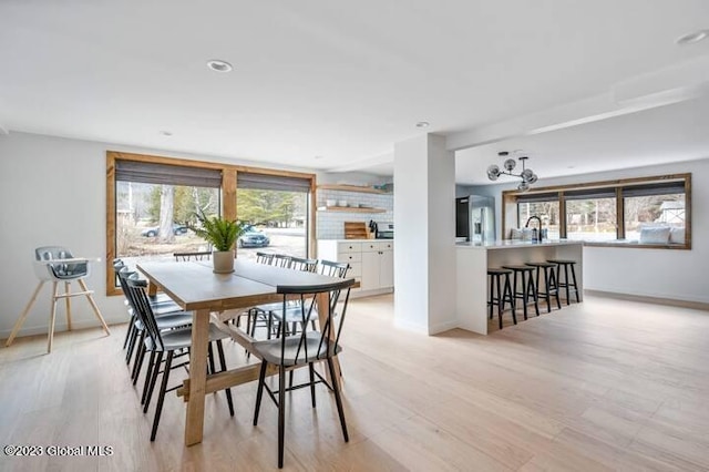 dining space with sink, a wealth of natural light, and light hardwood / wood-style flooring