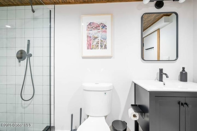 bathroom with a tile shower, vanity, and toilet