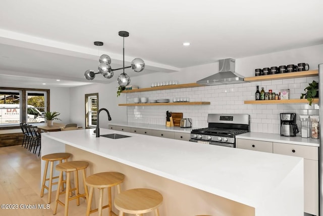 7913 Main St, Hunter, NY 12442 - kitchen with tasteful backsplash, wall chimney exhaust hood, a breakfast bar, gas range, and sink