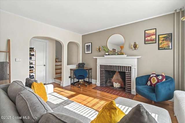 living room with wood finished floors, radiator heating unit, stairway, a fireplace, and crown molding