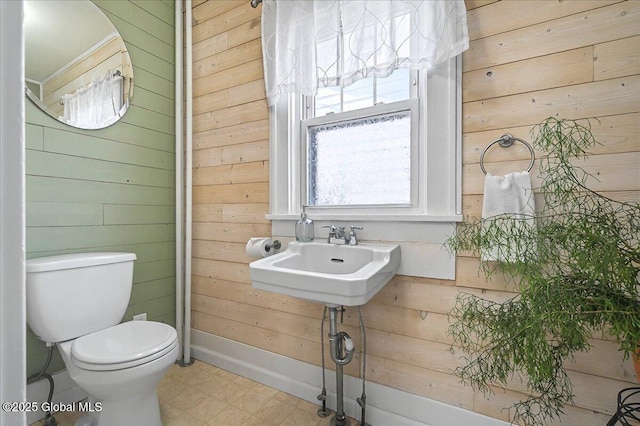 half bathroom featuring tile patterned floors, toilet, and wood walls