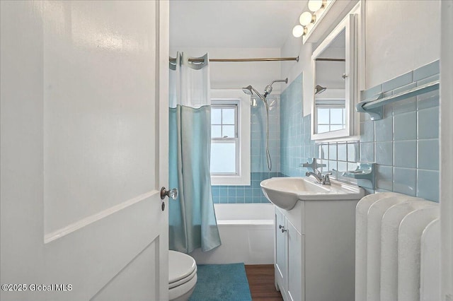 bathroom with shower / bathtub combination with curtain, toilet, tasteful backsplash, tile walls, and vanity