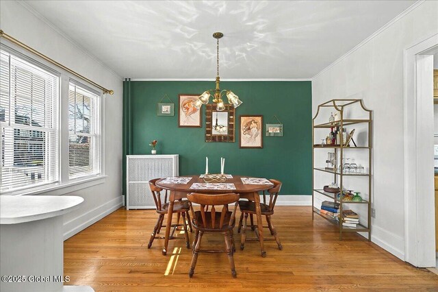 dining room with a notable chandelier, light wood-type flooring, baseboards, and ornamental molding