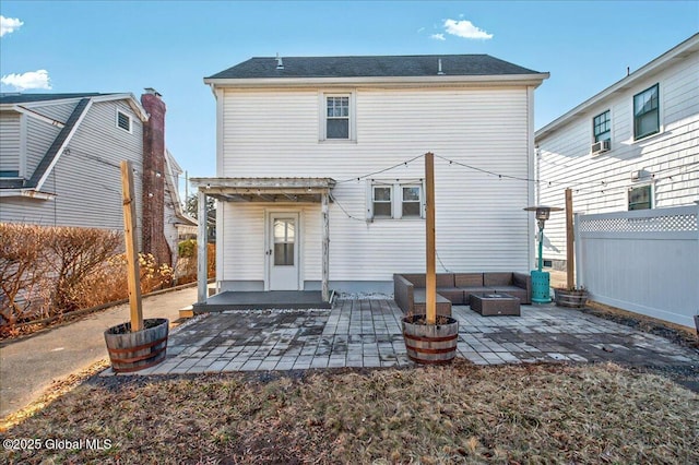 rear view of house with fence, an outdoor living space with a fire pit, and a patio area