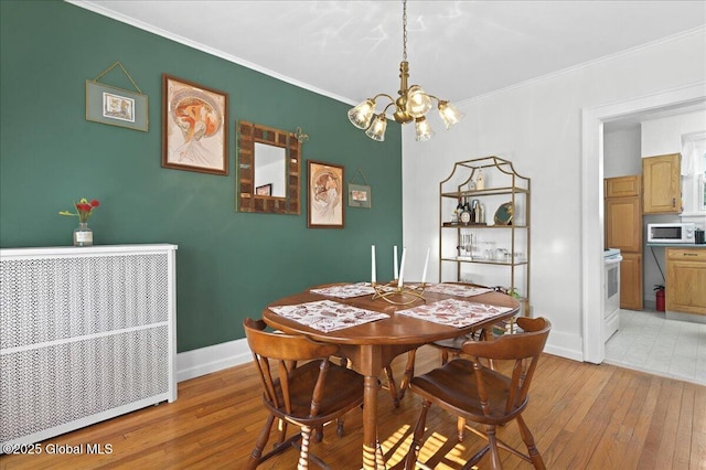 dining area featuring a notable chandelier, light wood-style floors, and ornamental molding