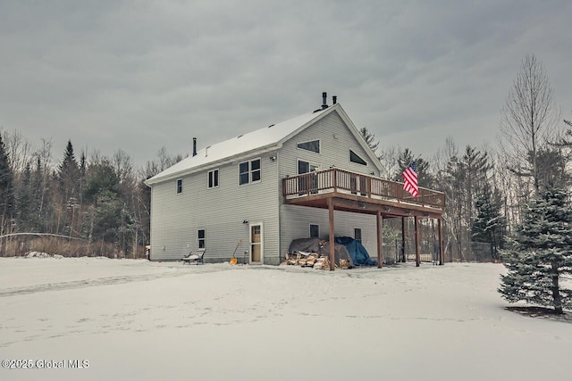 snow covered back of property featuring a wooden deck