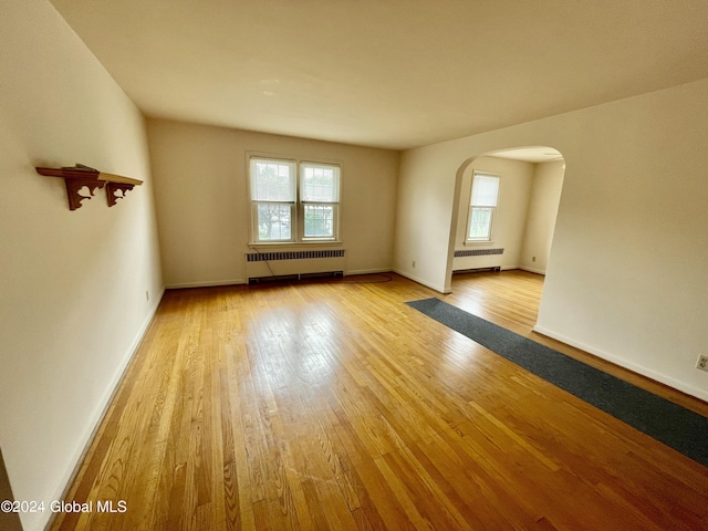 unfurnished room featuring radiator heating unit and light hardwood / wood-style flooring