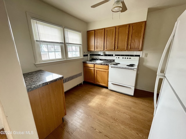 kitchen with white appliances, sink, light hardwood / wood-style flooring, ceiling fan, and radiator heating unit