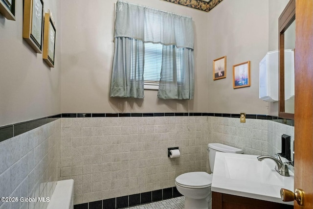 bathroom featuring vanity, tile walls, and toilet