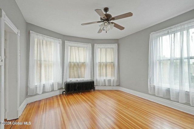 unfurnished sunroom with radiator, a healthy amount of sunlight, and ceiling fan