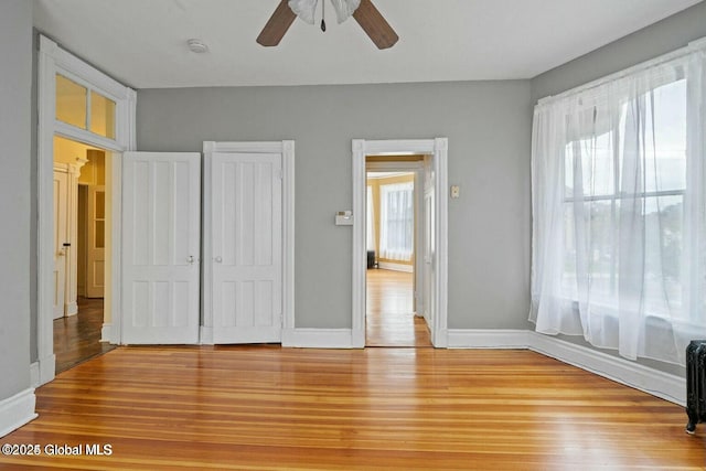 unfurnished bedroom with multiple windows, hardwood / wood-style floors, and ceiling fan