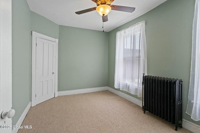 carpeted empty room with ceiling fan and radiator heating unit