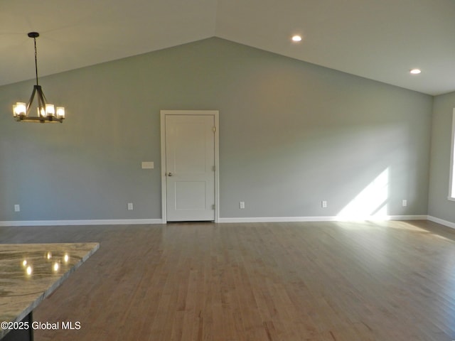 spare room featuring hardwood / wood-style floors, a chandelier, and vaulted ceiling