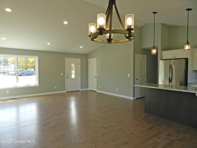 unfurnished living room featuring high vaulted ceiling, dark wood-type flooring, and a notable chandelier