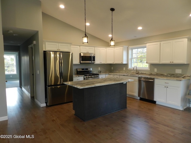 kitchen featuring white cabinetry, a center island, light stone countertops, hanging light fixtures, and appliances with stainless steel finishes