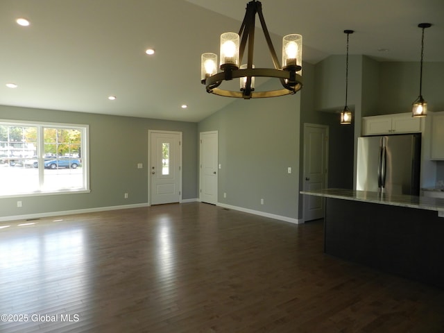 unfurnished living room with dark hardwood / wood-style floors, high vaulted ceiling, and an inviting chandelier