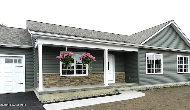 71 Bluebird Rd, Moreau, NY 12803 - property entrance with a porch, stone siding, an attached garage, and roof with shingles