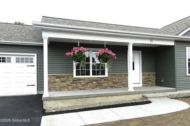 71 Bluebird Rd, Moreau, NY 12803 - property entrance featuring stone siding, covered porch, roof with shingles, and a garage