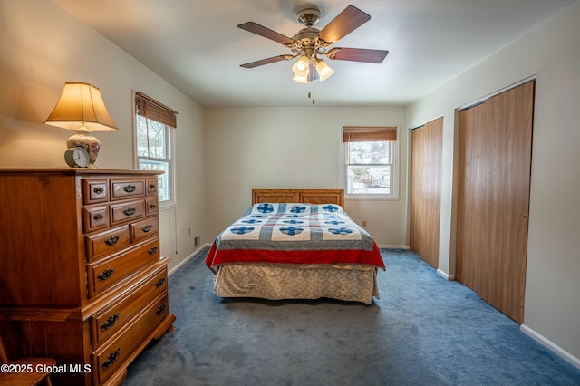 carpeted bedroom with ceiling fan, multiple closets, and multiple windows