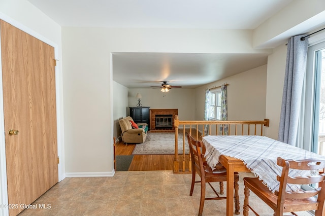 dining room with ceiling fan and a brick fireplace