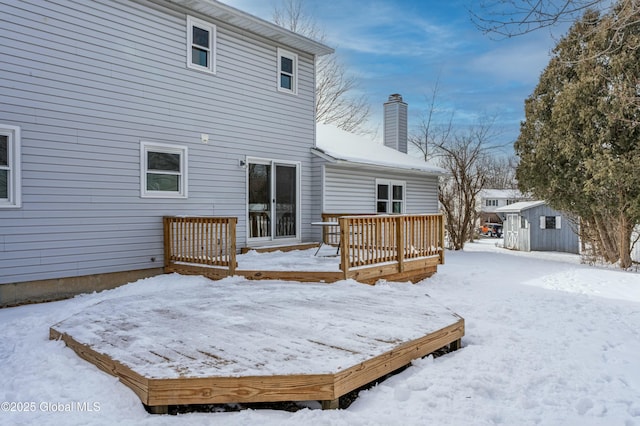 snow covered rear of property with a shed and a wooden deck