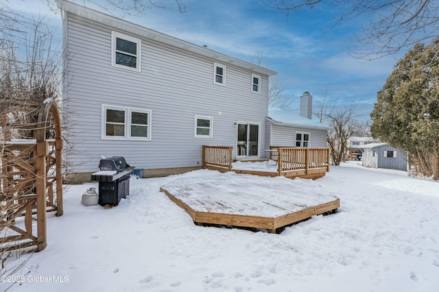 snow covered back of property featuring a wooden deck