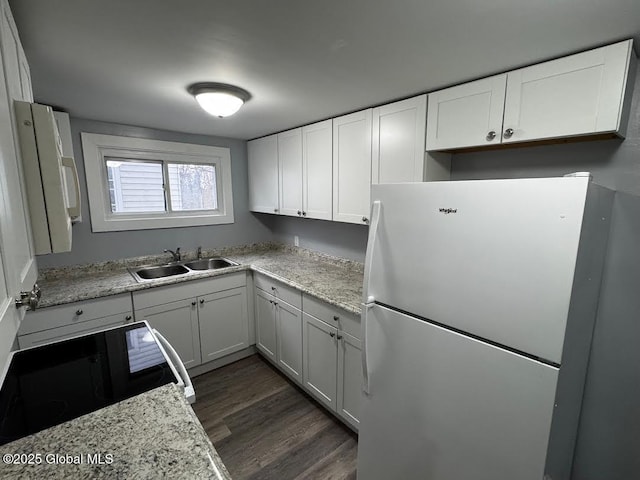 kitchen with white refrigerator, sink, dark hardwood / wood-style floors, light stone countertops, and white cabinetry