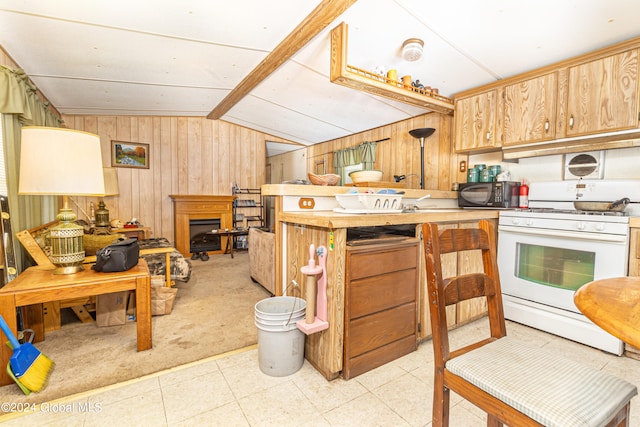 kitchen with lofted ceiling, wooden walls, and gas range gas stove