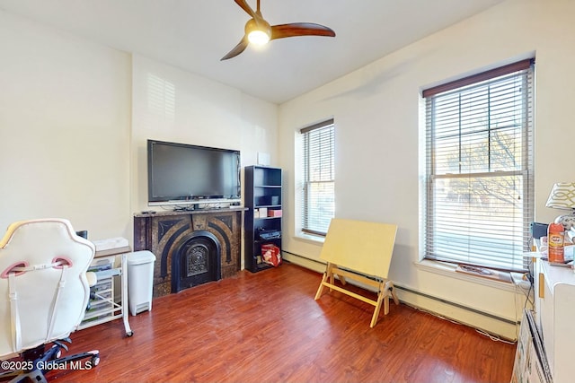 sitting room featuring hardwood / wood-style flooring, ceiling fan, and baseboard heating