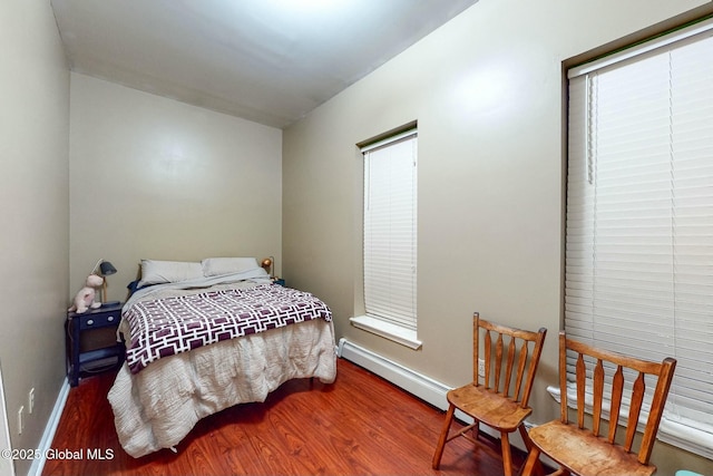 bedroom with hardwood / wood-style floors and a baseboard heating unit