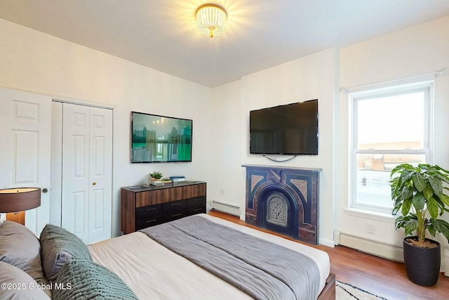 bedroom featuring wood-type flooring, a closet, and baseboard heating