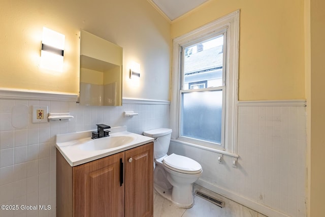 bathroom with toilet, vanity, tile patterned floors, and tile walls