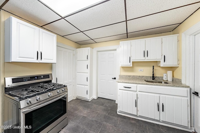 kitchen with white cabinetry, stainless steel gas range oven, a paneled ceiling, and sink