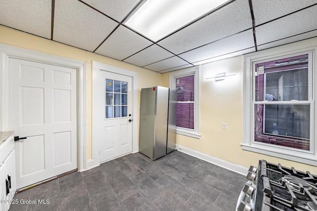 interior space featuring a paneled ceiling and stainless steel fridge