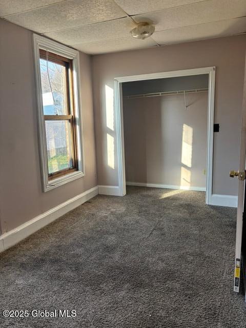 unfurnished bedroom featuring a closet and dark colored carpet