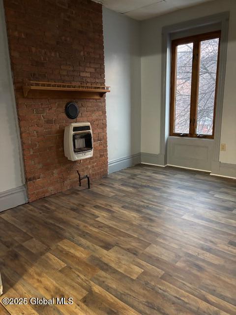 unfurnished living room featuring dark wood-type flooring and heating unit