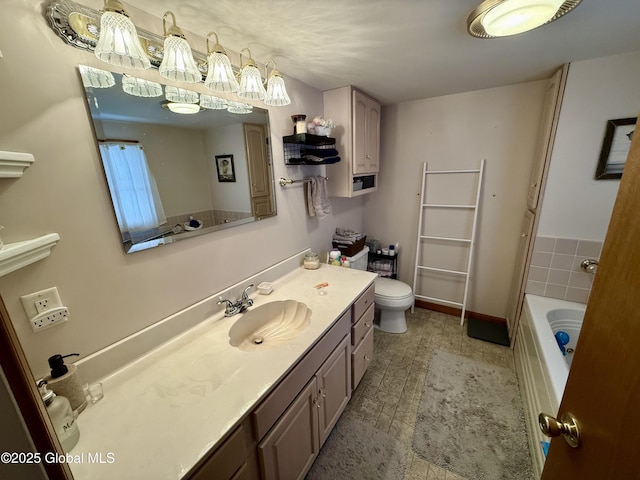 bathroom featuring vanity, a tub to relax in, and toilet