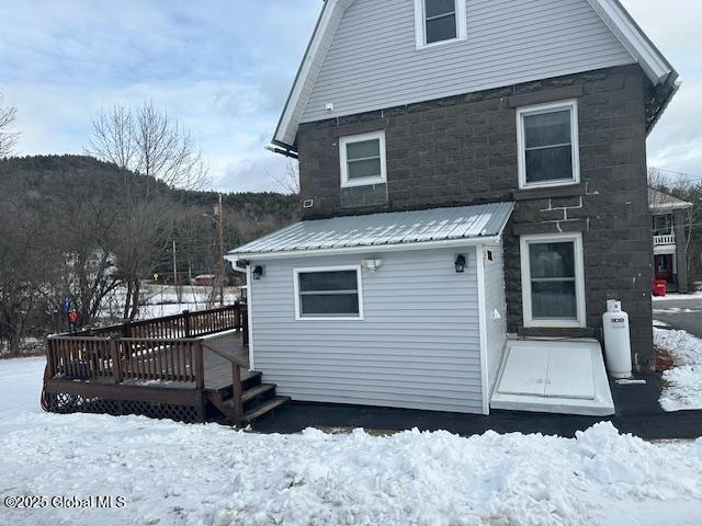 snow covered rear of property with a wooden deck