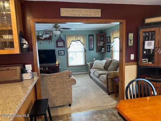 carpeted living room featuring baseboard heating and ceiling fan