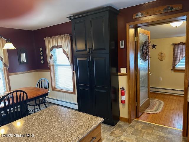 kitchen featuring light stone counters and baseboard heating