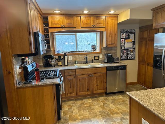 kitchen with light stone countertops, decorative backsplash, sink, and stainless steel appliances