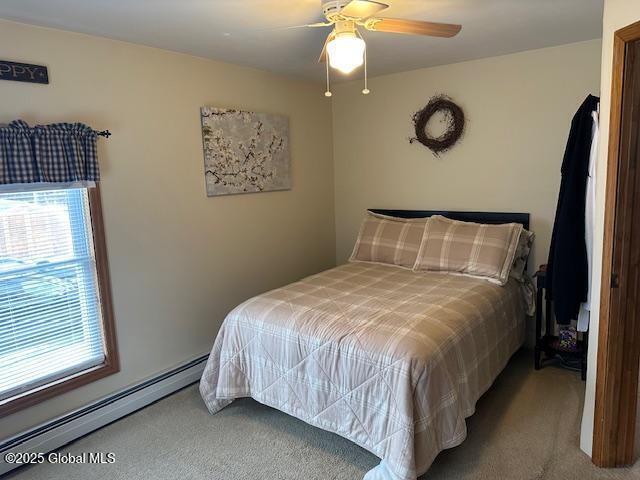 bedroom with carpet flooring, ceiling fan, baseboard heating, and multiple windows