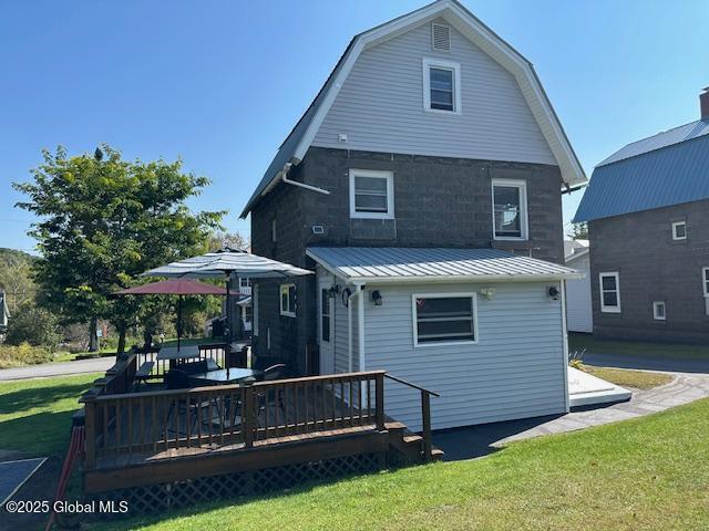 rear view of house with a deck and a lawn