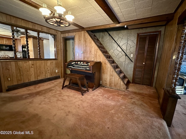 misc room featuring wooden walls, carpet floors, and a notable chandelier