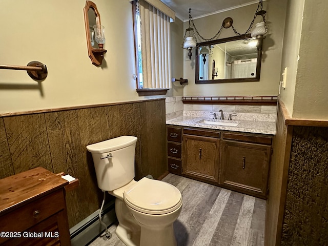 bathroom featuring vanity, wood-type flooring, a baseboard heating unit, and toilet