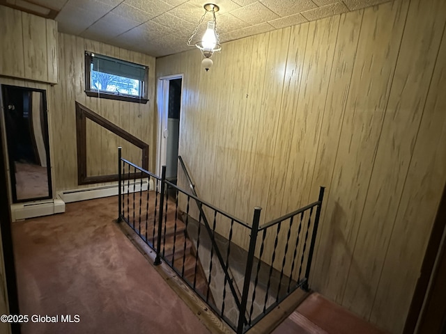 stairway featuring baseboard heating, carpet, and wood walls